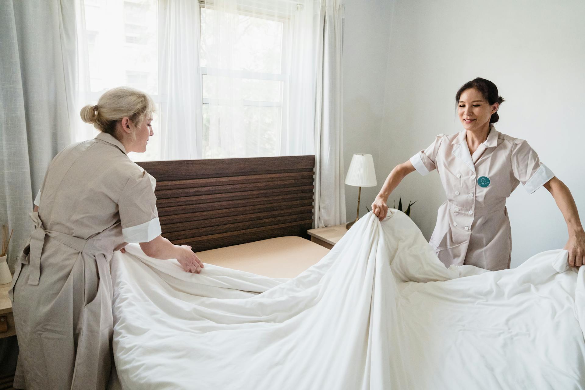 2 women cleaning the bed