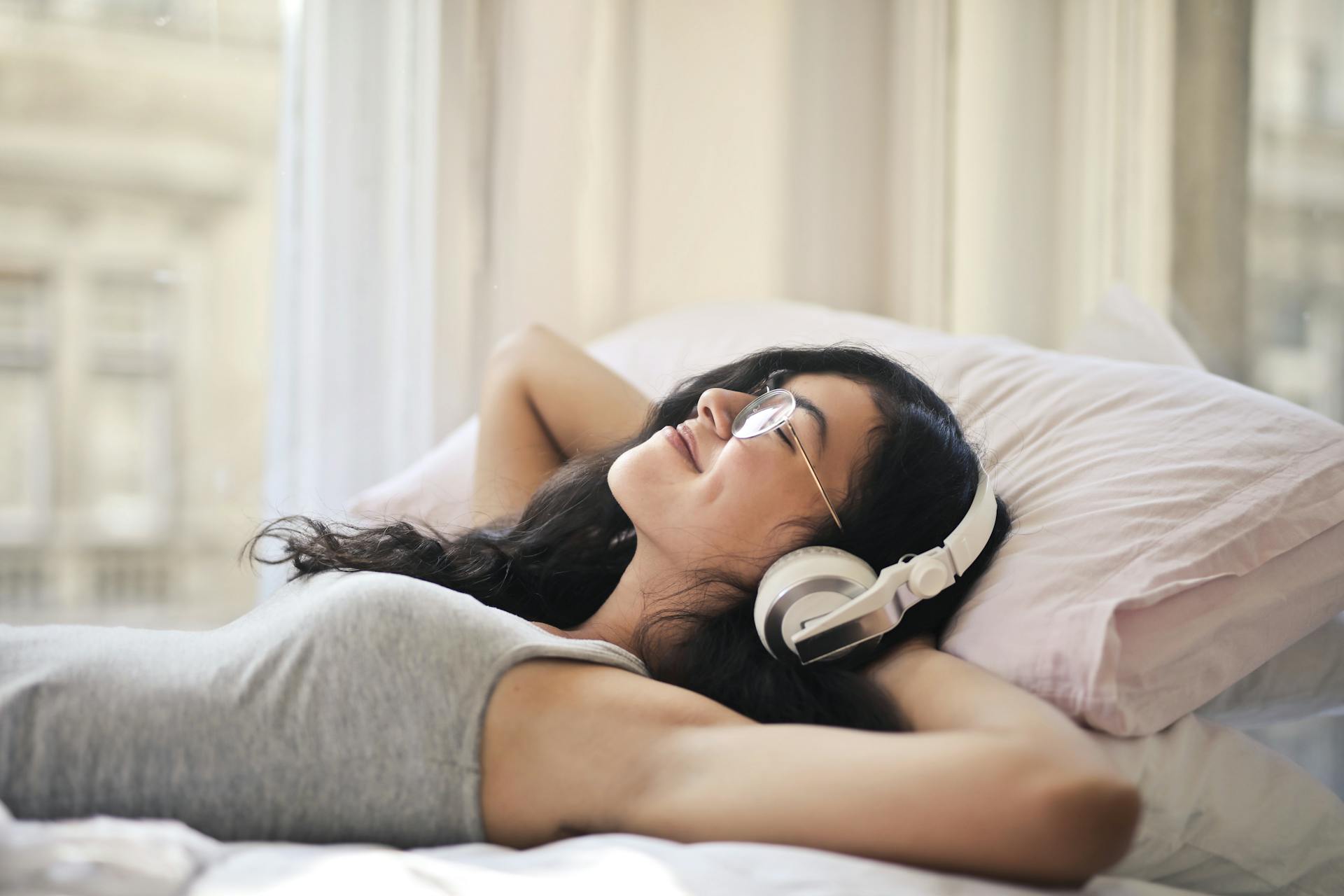 Woman with headphones lying on a bed